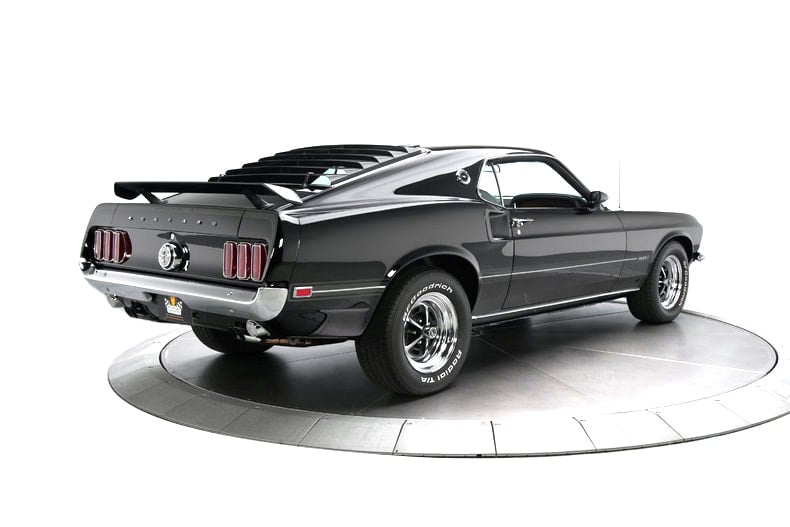 A black 1969 Ford Mustang parked on a turntable.