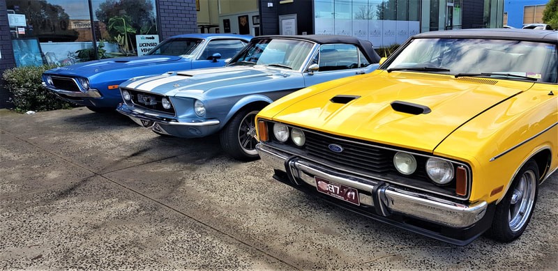 A line up of three classic Ford muscle cars on the TGS Muscle Cars; one is light blue, one royal blue and one yellow.